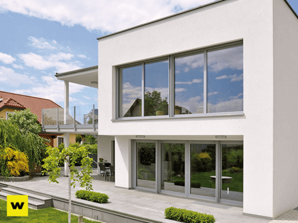 Modernes Einfamilienhaus mit großen Fenstern, Terrasse und gepflegtem Garten im Sommer.